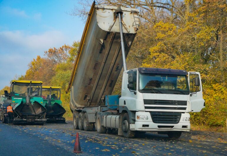 Lkw mit Mulde kippt Asphaltmischgut in den Straßenfertiger